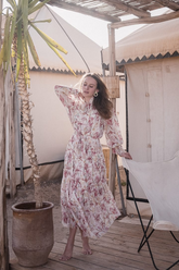 a lady in a pink silk tiered floral printed dress with long sleeves